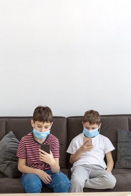 Children playing on smartphones while wearing medical masks