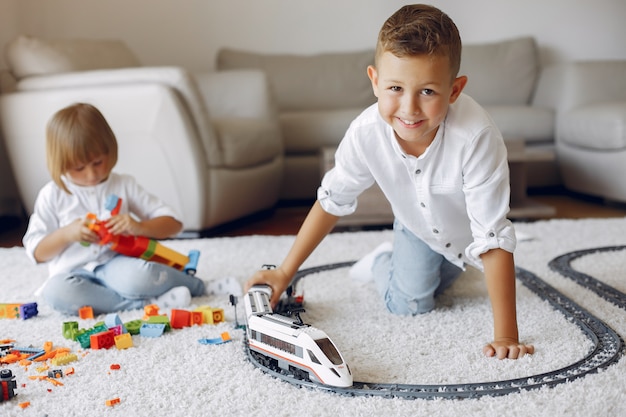 Children playing with lego and toy train in a playing room