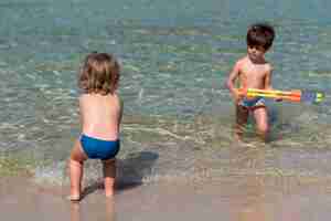 Foto gratuita bambini che giocano con pistole ad acqua in spiaggia