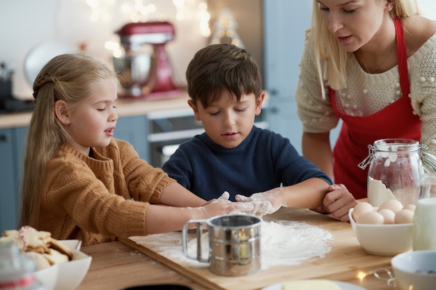 クリスマスのクッキーのためにペストリーを準備している子供たち