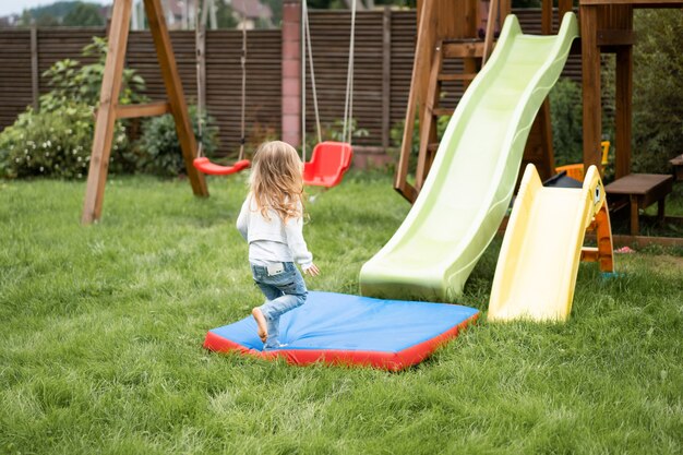 子供たちが子供たちの滑り台から乗る、姉妹たちが庭で一緒に遊ぶ