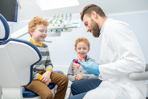 歯科医院で人工顎の歯を磨く方法を男の子に示す子供の歯科医