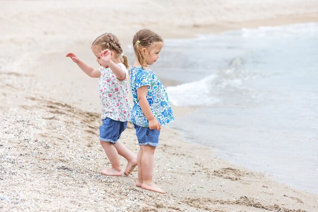 Дети на морском пляже. Близнецы собираются вдоль морской воды.