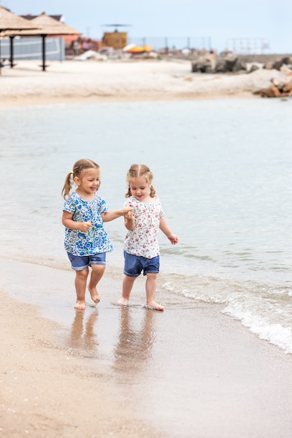 海のビーチで子供たち。海の水に沿って行く双子。