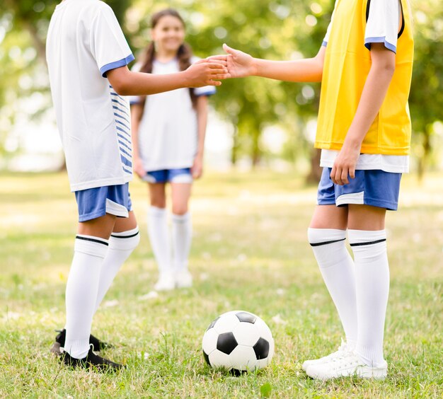 Children shaking hands before a football match outdoors