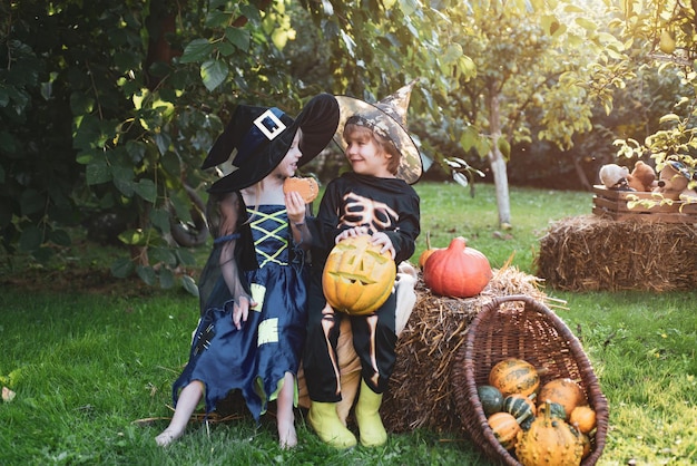 Children sister and brother with pumpkin dressed like skeleton and witch for halloween party hallowe...