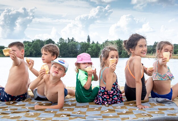 Children sit on a blanket by the river and relax after swimming.
