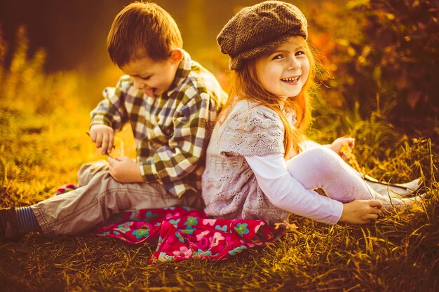 Children sit side by side on a plaid 