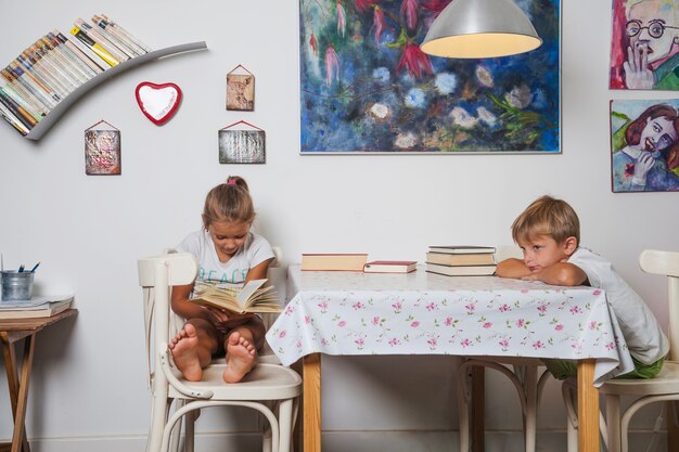 Дети, сидящие на столе с книгами