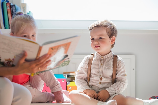 Free photo children sitting looking at book