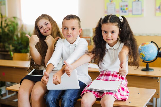 Children sitting on school desk gesturing