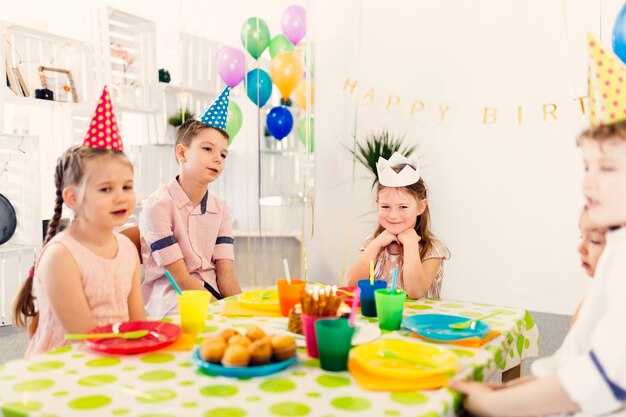 誕生日にテーブルに座っている子供たち