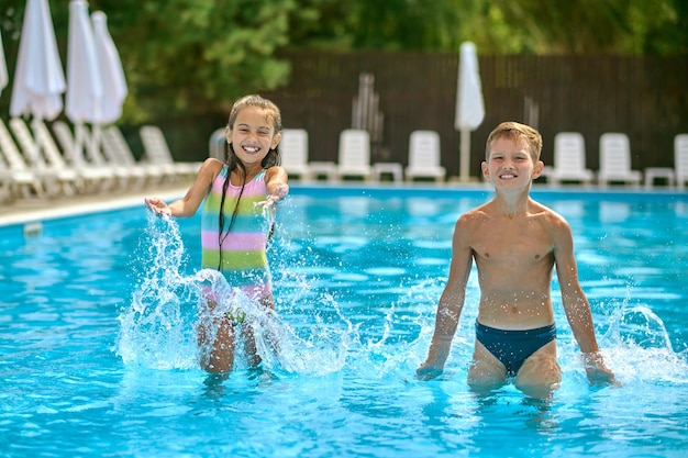 屋外プールの水の中に立っている子供たち