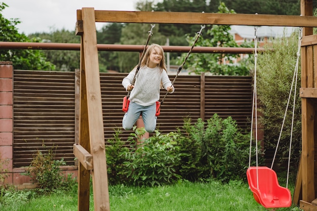 children on the swing. girl swinging on a swing in the yard. summer fun.