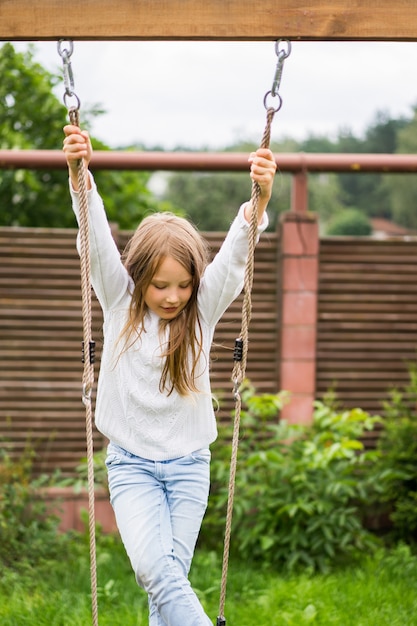 ブランコに乗っている子供たち。女の子が庭のブランコに揺れています。夏のお楽しみ。