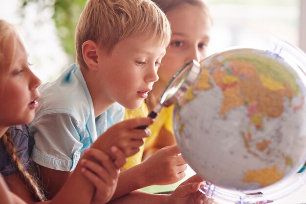 Дети, использующие увеличительное стекло в географии
