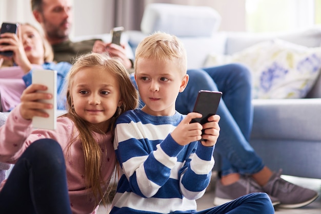 居間で携帯電話を使用している子供たち