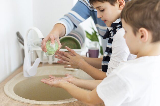 Children washing their hands with the help of their mother