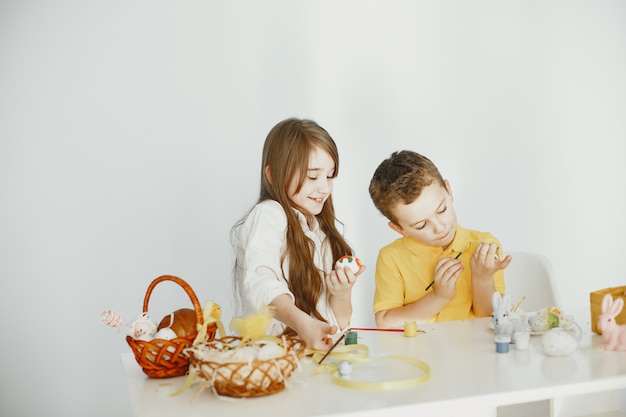 Children with bunny ears. Painted Easter eggs. Children with paints and brushes.