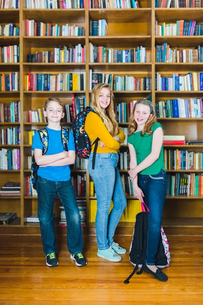 Дети с школьными рюкзаками, стоящими в библиотеке