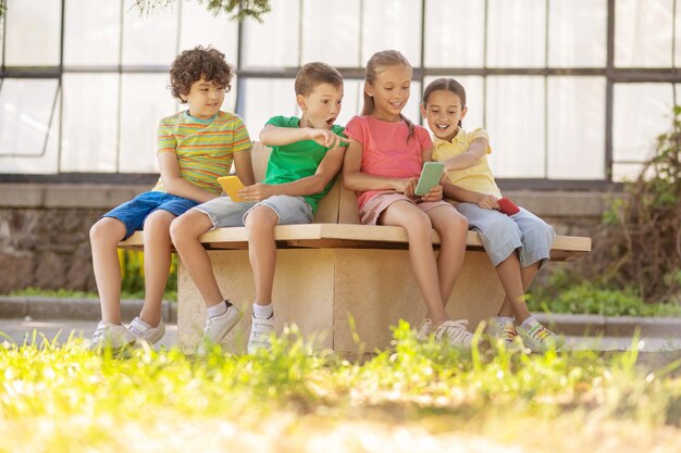 Children with smartphones sitting in park