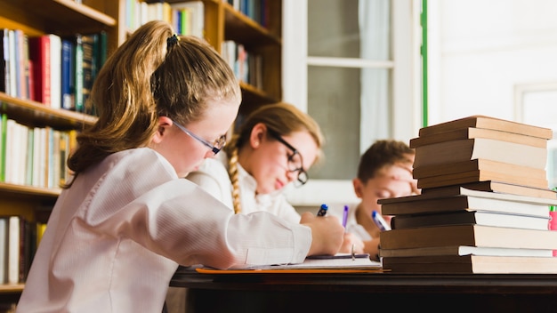 Children writing in copybooks in library 