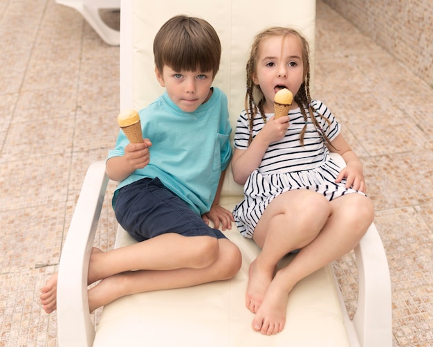 Дети сидят на кровати солнца и едят мороженое