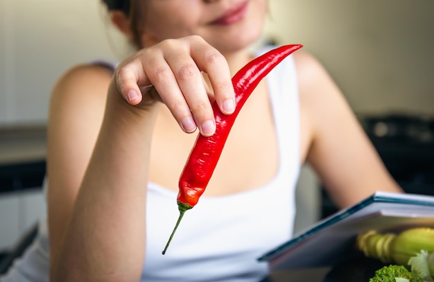 Peperoncino in mani femminili in cucina su uno sfondo sfocato