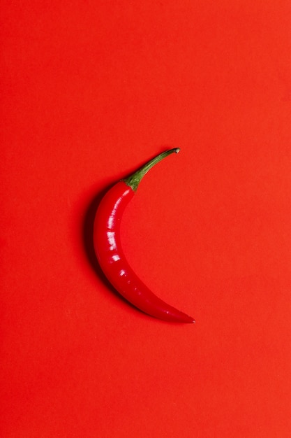 Chili pepper isolated on red, top view