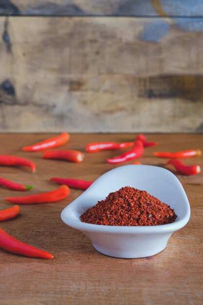 Chili powder and fresh peppers on old wood table. Premium Photo