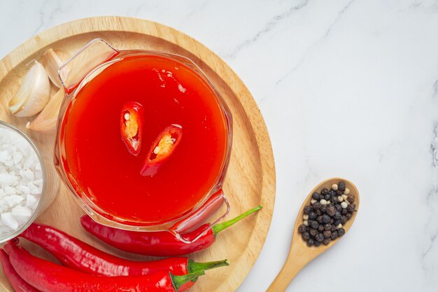 Chili sauce and peppers on white surface