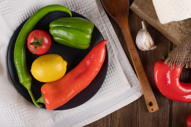 Peperoncini, pomodoro e limone in un piatto nero