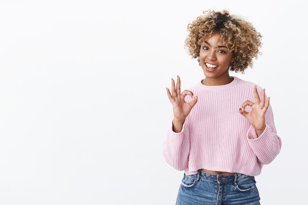 Chill everything perfect. Portrait of happy and delighted female african-american customer recommending good quality product showing ok gesture and smiling satisfied over white wall
