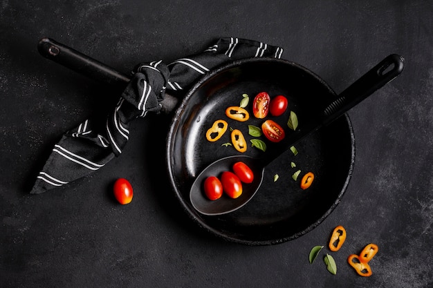 Chilli pepper and tomatoes in black frying pan flat lay