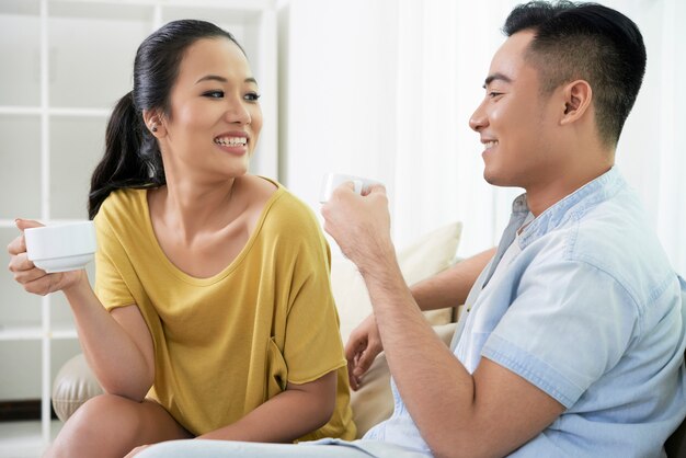 Chilling couple with coffee cups on sofa