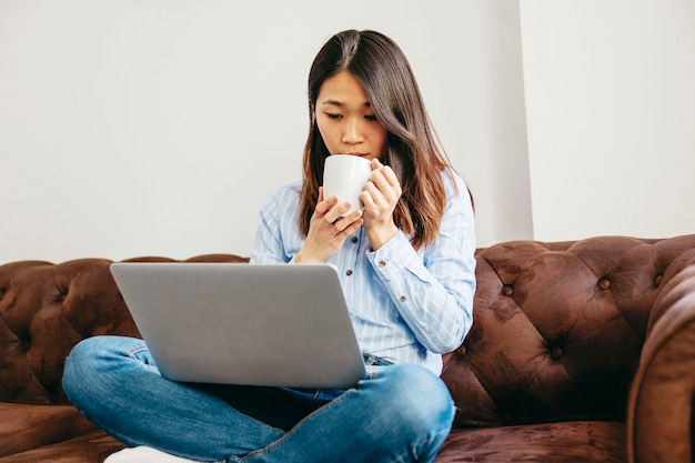 Chilling girl having coffee and watching laptop