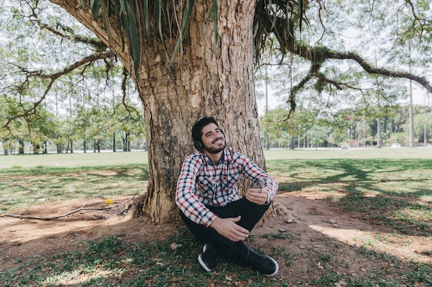Free photo chilling man in headphones under tree