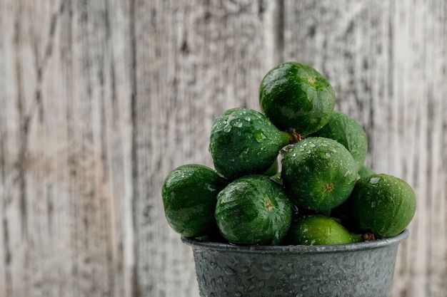 Free photo chilly figs in a mini bucket on a grungy wooden wall. close-up.