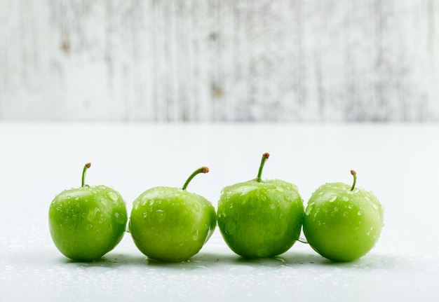 Free photo chilly green plums on white and grungy wall. side view.