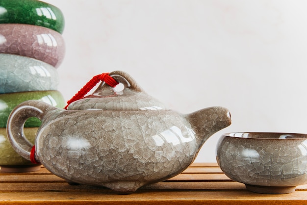 Free photo chinese ceramic teapot and tea cups on wooden desk against wall