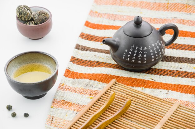 Чайник из китайской глины с цветущим чайным шариком на белом фоне