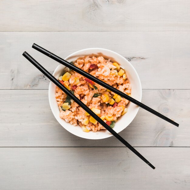 Chinese fried rice bowl with black chopsticks on wooden table