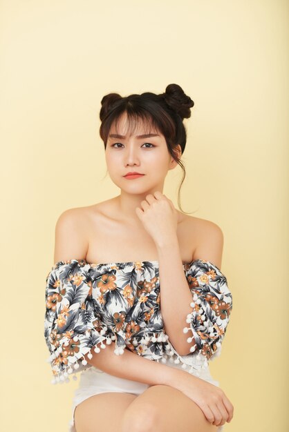 Chinese girl in bare shoulder top sitting and posing in studio