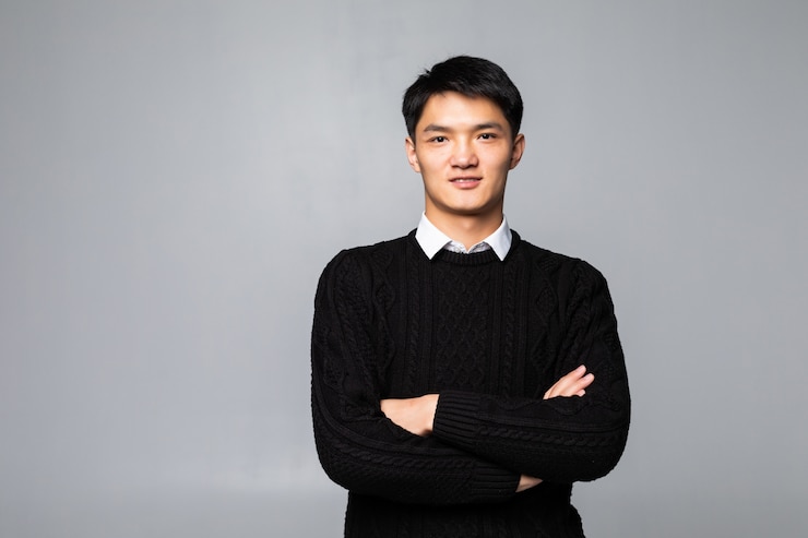 無料Photo 笑みを浮かべて、白い壁に分離されて笑っている中国のハンサムな男