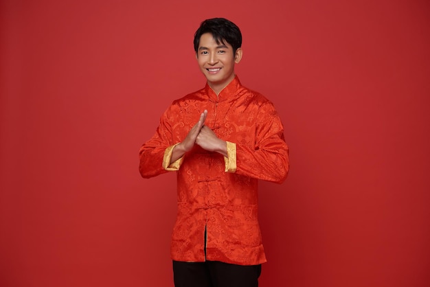 Китайский новый год 2024 Азиатский мужчина в красной традиционной одежде с жестом поздравления
