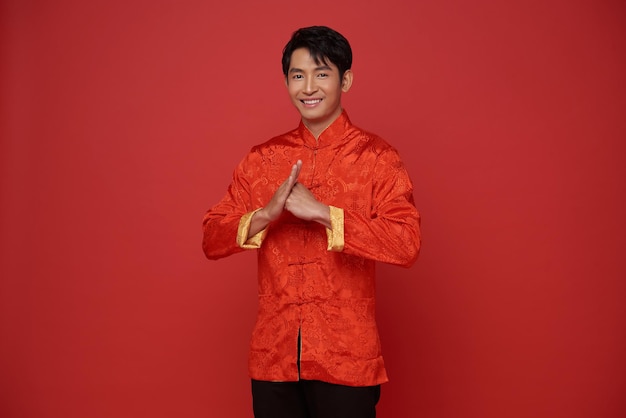 Chinese new year 2024 Asian man wearing red traditional clothing with gesture of congratulation