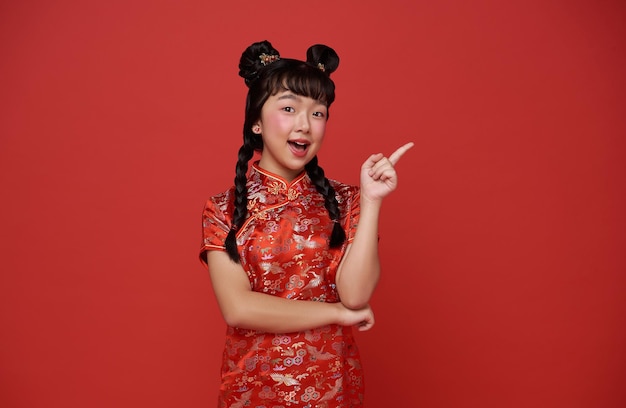 Chinese new year Asian child girl wearing traditional cheongsam qipao dress and hand pointing finger