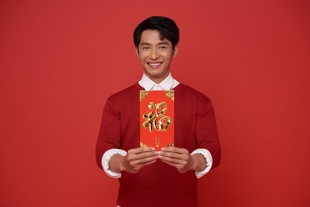 Китайский новый год Азиатский мужчина с ангпао или красным пакетом денежный подарок изолирован на красном фоне