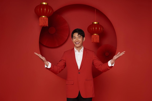 Chinese new year Asian man wearing red suit dress with gesture of welcome chinese new year 2024