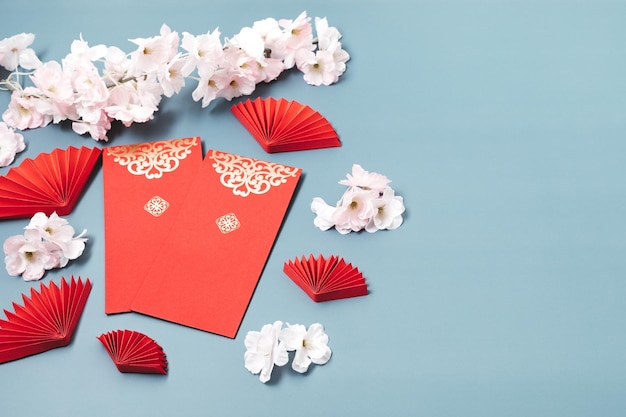 Chinese new year festival decoration over blue background. traditional lunar new year flat lay with cherry blossom and red pockets. top view